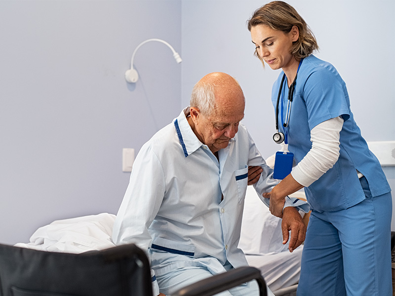 Pflegekraft im Pflegeheim in Salzwedel unterstützt älteren Patienten fürsorglich beim Aufstehen.