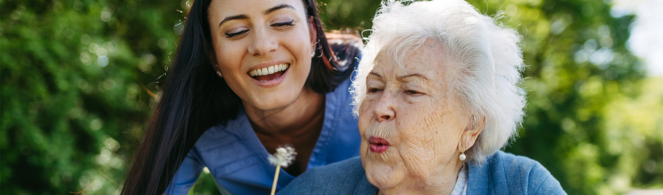 Pflegekraft im Pflegeheim in Salzwedel begleitet Seniorin im Rollstuhl beim Pflücken von Blumen im Park